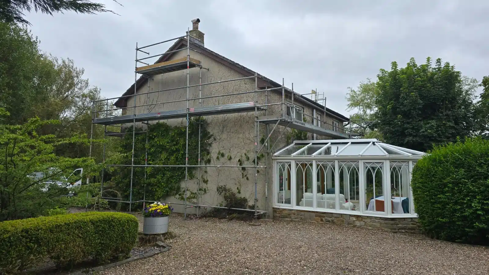 Domestic scaffolding erected on the gable end and side elevation of a rendered house for chimney and roofline access