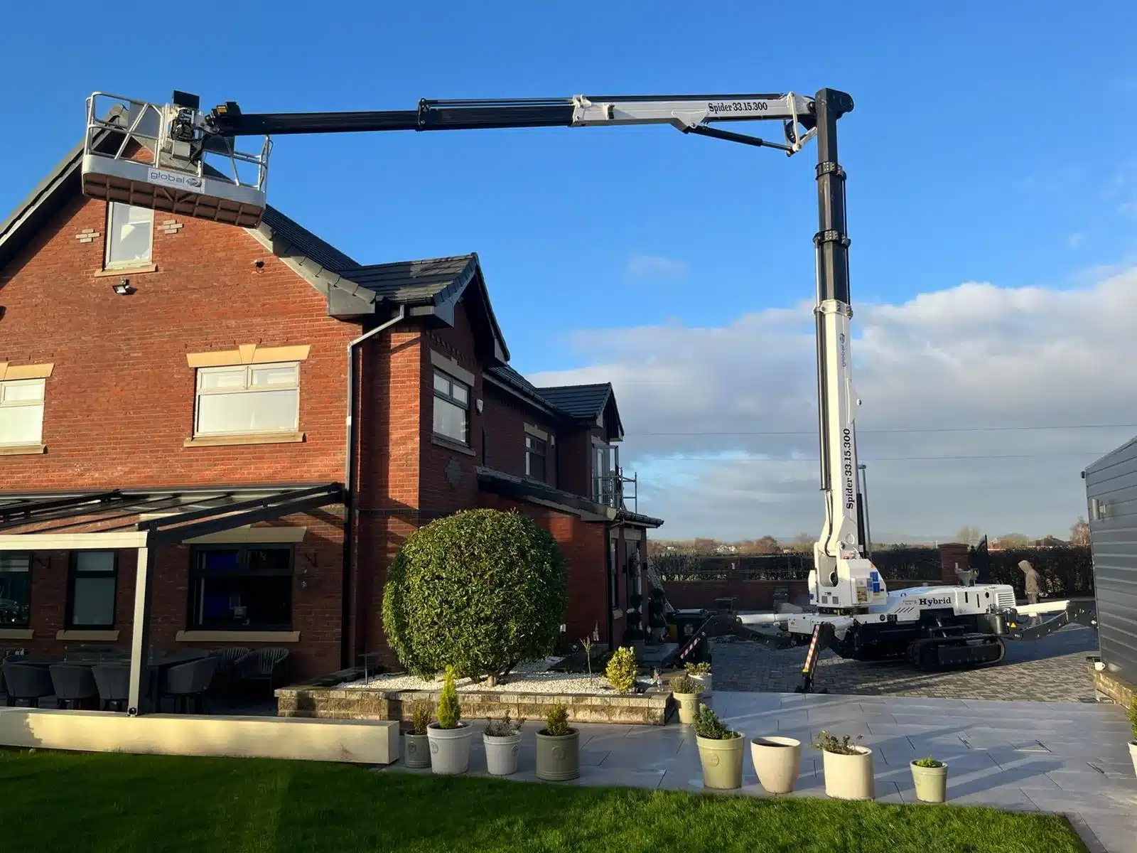 Global Platforms Spider 33.15.300 hybrid spider MEWP extended over a two-storey house to reach roofline access