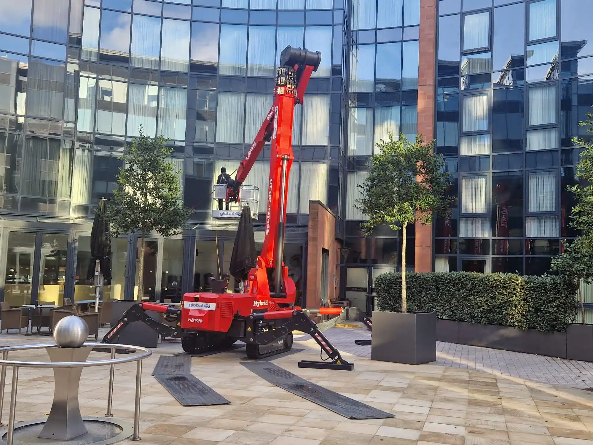 Platform Basket Spider 33.15 hybrid spider MEWP extended in a glass-fronted courtyard, outriggers set on protective mats